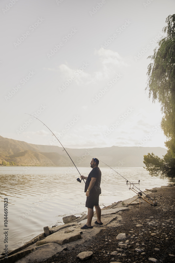 Fisherman fishing on a lake during a sunny day Fisherman fishing on a lake during a sunny day