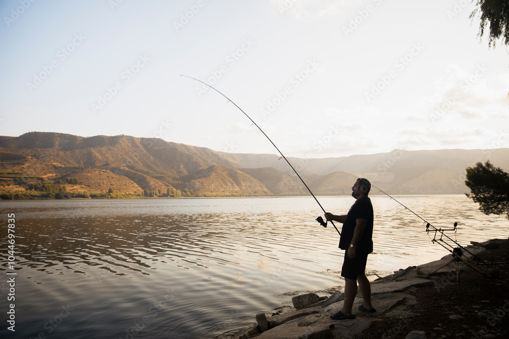 Fisherman fishing on a lake during a sunny day Fisherman fishing on a lake during a sunny day
