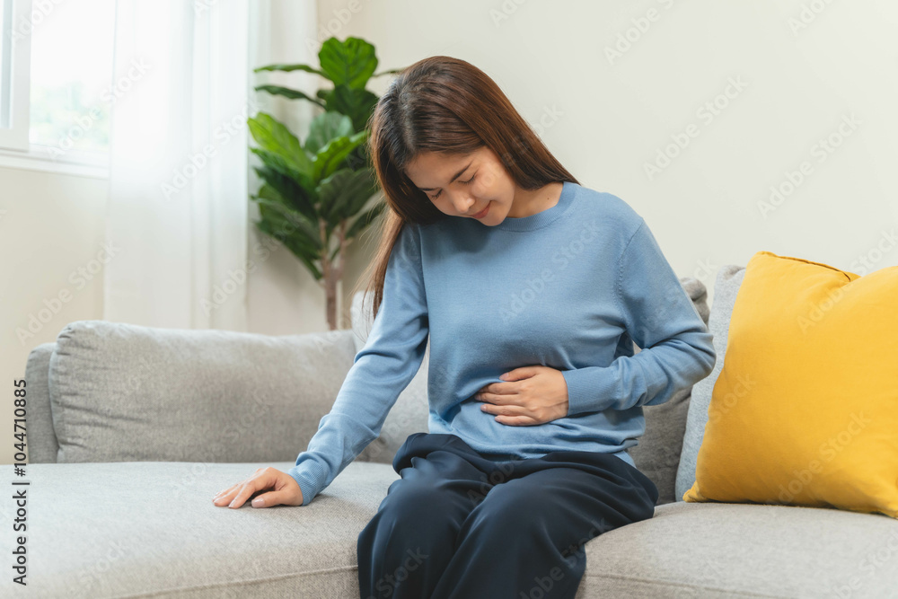Close-up hands of young woman putting on her belly and feeling pain from cycle period on the sofa. Close-up hands of young woman putting on her belly and feeling pain from cycle period on the sofa.