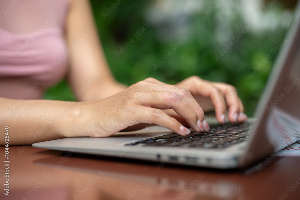 A close-up of a woman working on her laptop, typing on the laptop keyboard, working remotely. A close-up of a woman working on her laptop, typing on the laptop keyboard, working remotely.