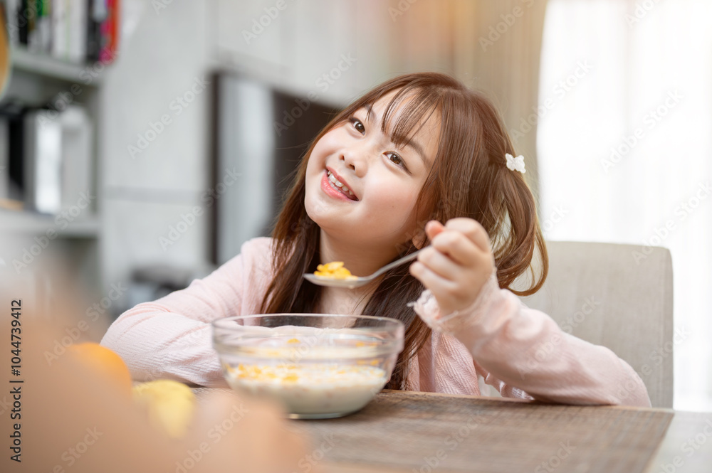 A young, adorable Asian girl is enjoying having breakfast with her mom at a dining table. A young, adorable Asian girl is enjoying having breakfast with her mom at a dining table.
