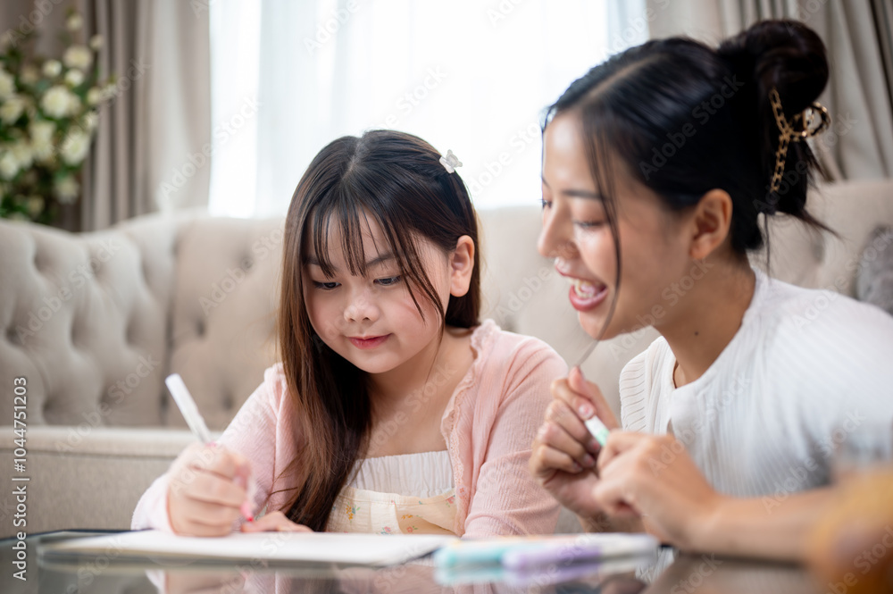 A young, adorable Asian girl is enjoying drawing and coloring with her mom in the living room. A young, adorable Asian girl is enjoying drawing and coloring with her mom in the living room.