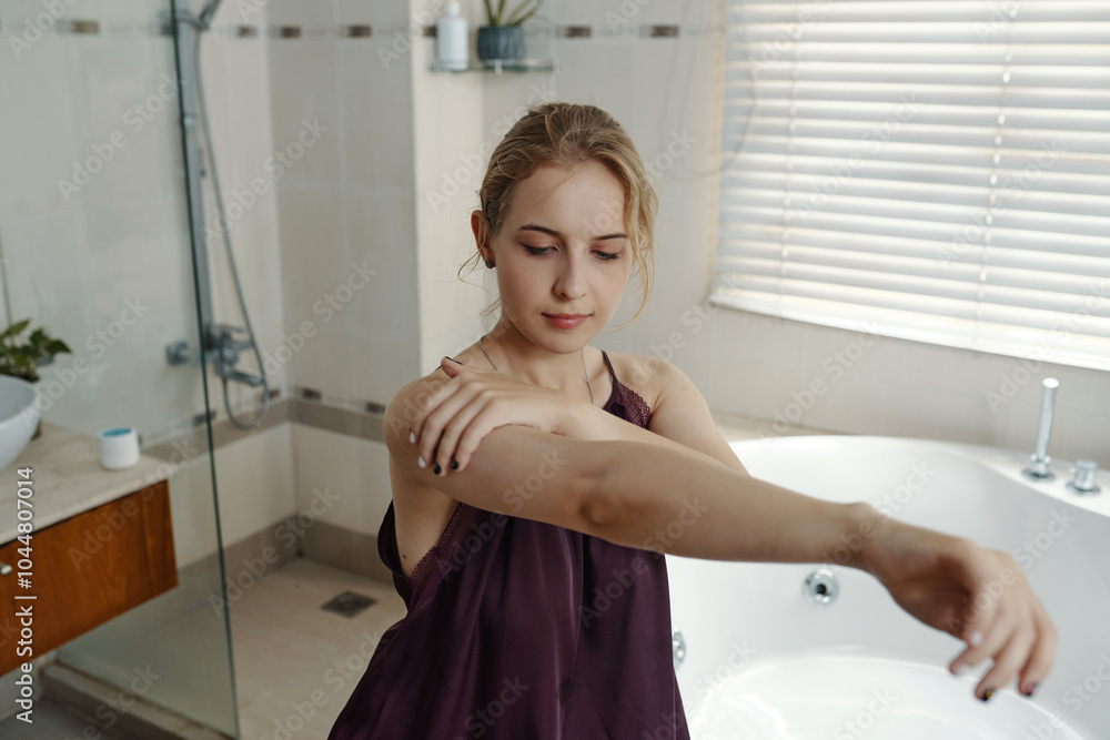 Young woman in bathroom applying body lotion, focusing on smooth, healthy skin care practices during her morning routine, surrounded by serene interior design Young woman in bathroom applying body lotion, focusing on smooth, healthy skin care practices during her morning routine, surrounded by serene interior design