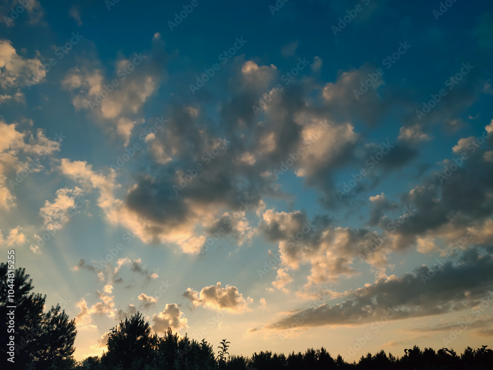 Obraz premium Vivid orange clouds over the forest at sunset. Colorful clouds on the dramatic sunset sky.