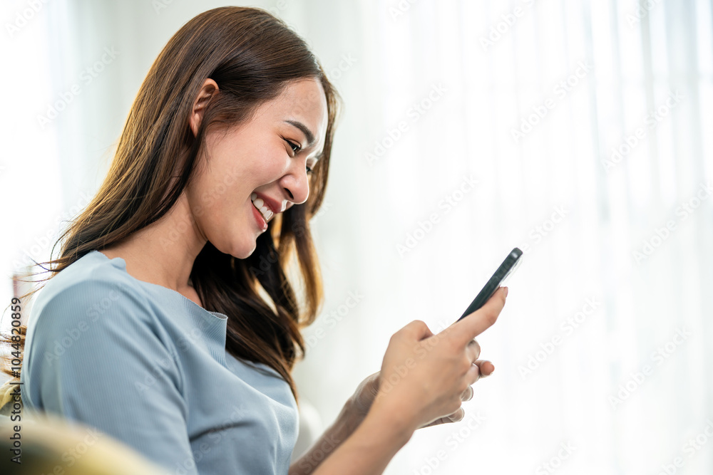 Asian beautiful woman sitting on sofa and swipe mobile phone in house. Asian beautiful woman sitting on sofa and swipe mobile phone in house.