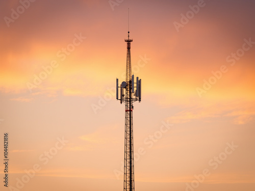 Sunset over a mobile phone tower silhouetted against a blue sky, representing modern communication technology and wireless networks