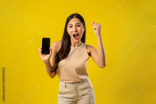 Portrait of Asian woman holding smartphone in isolated yellow background. 