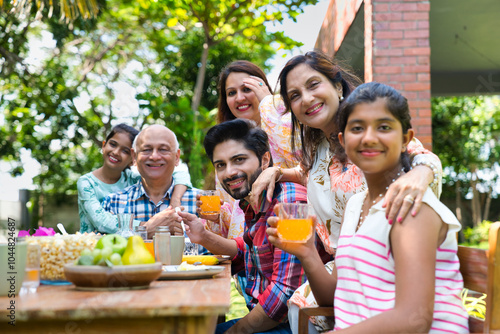 Indian family enjoying breakfast outdoors, happily posing for a group photo around the table photo