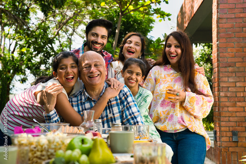 Photography Indian family enjoying breakfast outdoors, happily posing for a group photo arou