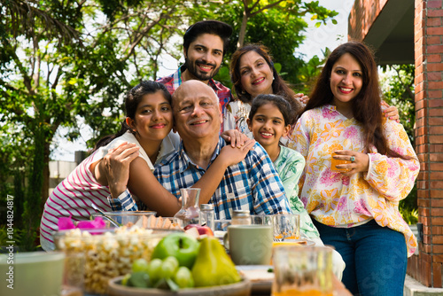 Photography Indian family enjoying breakfast outdoors, happily posing for a group photo arou