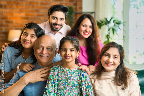 Photography Closeup of Indian family of six sitting together on a sofa in a lavish home, joy