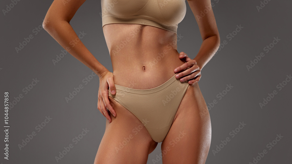 Close-up of woman's torso in beige lingerie against warm grey background. Fit, smooth and tanned upper body. Concept of female health dieting, natural beauty, wellness. Ad Close-up of woman's torso in beige lingerie against warm grey background. Fit, smooth and tanned upper body. Concept of female health dieting, natural beauty, wellness. Ad