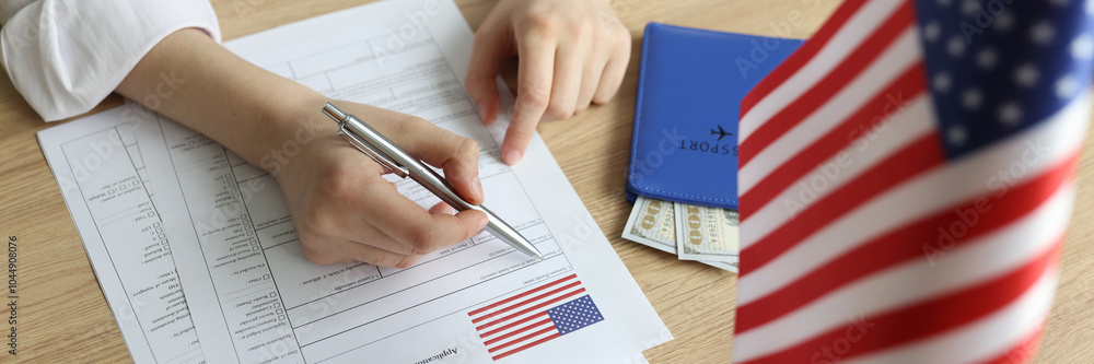 Young woman fills in visa application form near USA flag