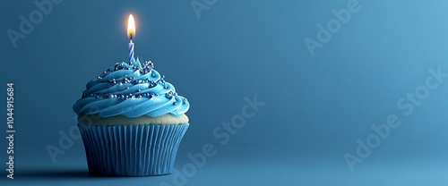 A single blue cupcake with a lit candle on top, on a blue background.