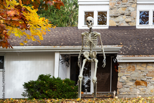 Spooky giant human two-story Halloween decoration skeleton in front of house seen during a fall afternoon, Quebec City, Quebec, Canada