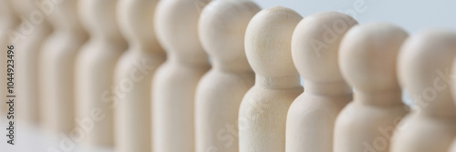 Small wooden figures lined up in long row on white table