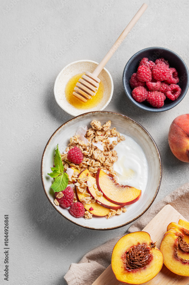 Flat lay of greek natural yogurt with oat granola or muesli, peach, raspberry and honey in a bowl on a light background Flat lay of greek natural yogurt with oat granola or muesli, peach, raspberry and honey in a bowl on a light background