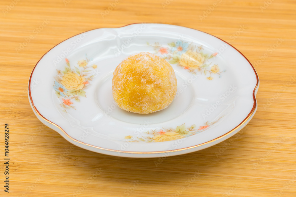 Plate with a panellet on a wooden surface. Panellets are traditional sweets for All Saints' Day in Catalonia, the Balearic Islands, Levante and Aragon. Plate with a panellet on a wooden surface. Panellets are traditional sweets for All Saints' Day in Catalonia, the Balearic Islands, Levante and Aragon.