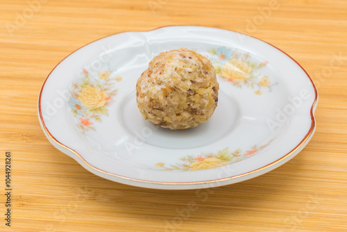 Plate with a panellet on a wooden surface. Panellets are traditional sweets for All Saints' Day in Catalonia, the Balearic Islands, Levante and Aragon.