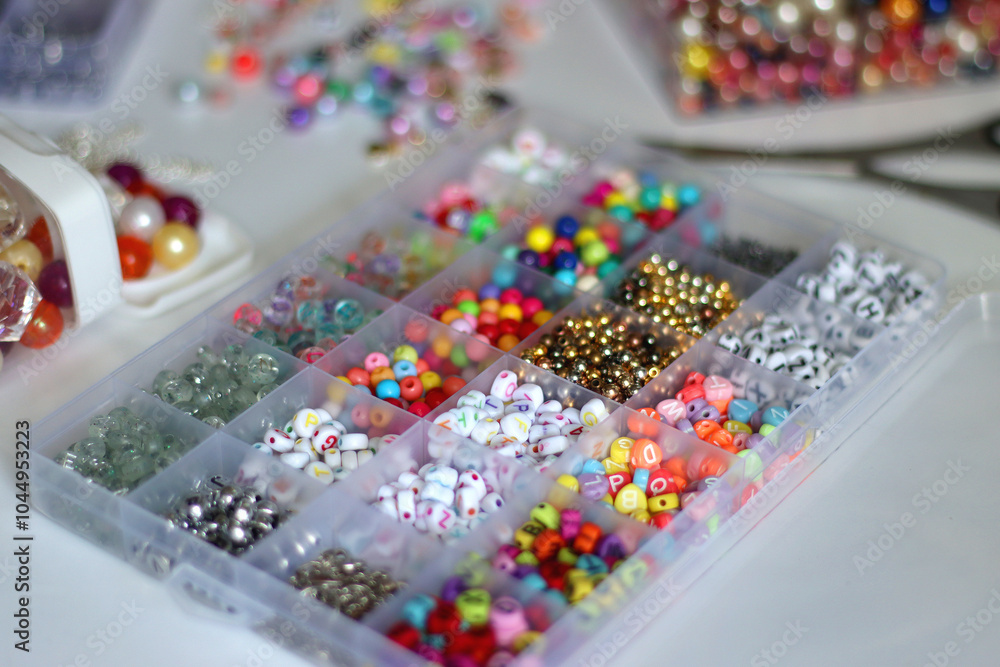 Colorful beads, letter beads, threads and other jewelry making supplies on white background. Making friendship bracelets concept. Selective focus.
