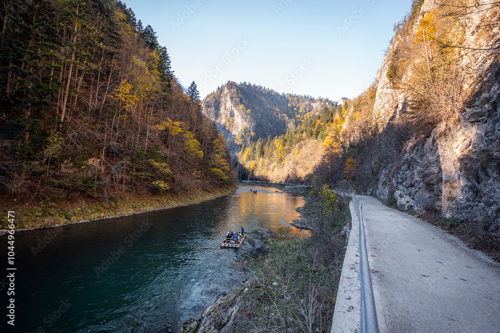 Wooden raft (tratwa flisacka) filled with tourists floating on the Dunajec river in the Pieniny National Park. The Dunajec Gorge in autumn. Mountains. Traditional rafting . Szczawnica, Poland