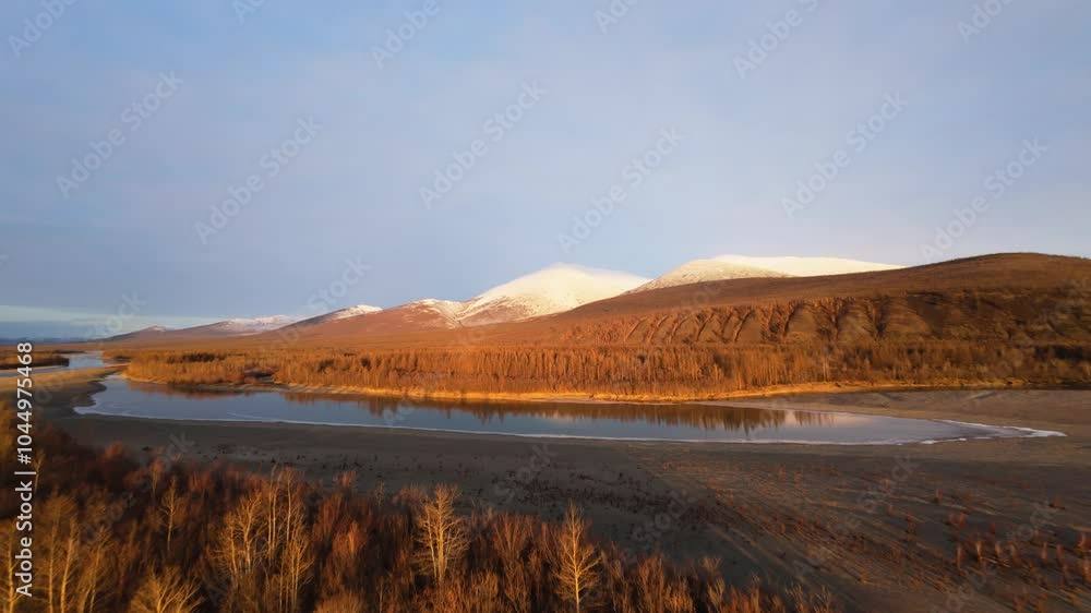 Witness the stunning beauty of Yakutia as a drone soars over tranquil rivers and majestic mountains, showcasing the unique interplay of light and shadow during the golden hour. Witness the stunning beauty of Yakutia as a drone soars over tranquil rivers and majestic mountains, showcasing the unique interplay of light and shadow during the golden hour.