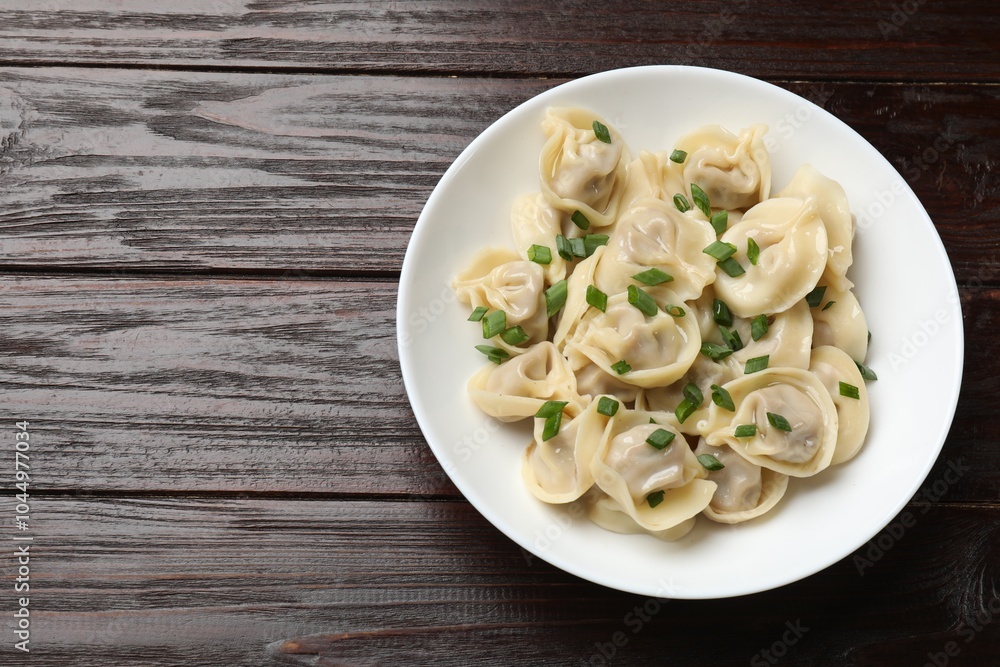 Delicious pelmeni with green onion on wooden table, top view. Space for text Delicious pelmeni with green onion on wooden table, top view. Space for text