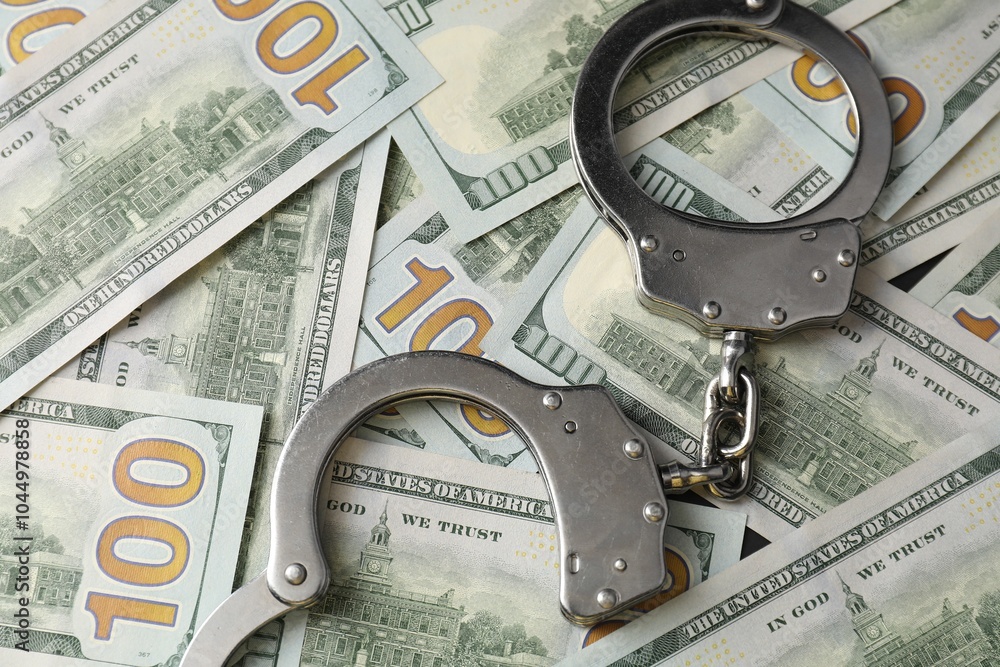 Corruption concept. Handcuffs on dollar banknotes, closeup Corruption concept. Handcuffs on dollar banknotes, closeup