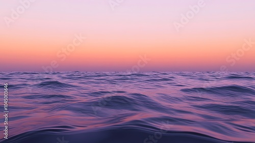 A calm sea at sunset, with the horizon blending into a gradient of purples and oranges, creates an atmosphere that feels serene and peaceful.