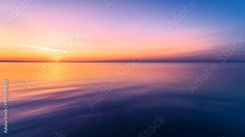 A calm sea at sunset, with the horizon blending into a gradient of purples and oranges, creates an atmosphere that feels serene and peaceful.