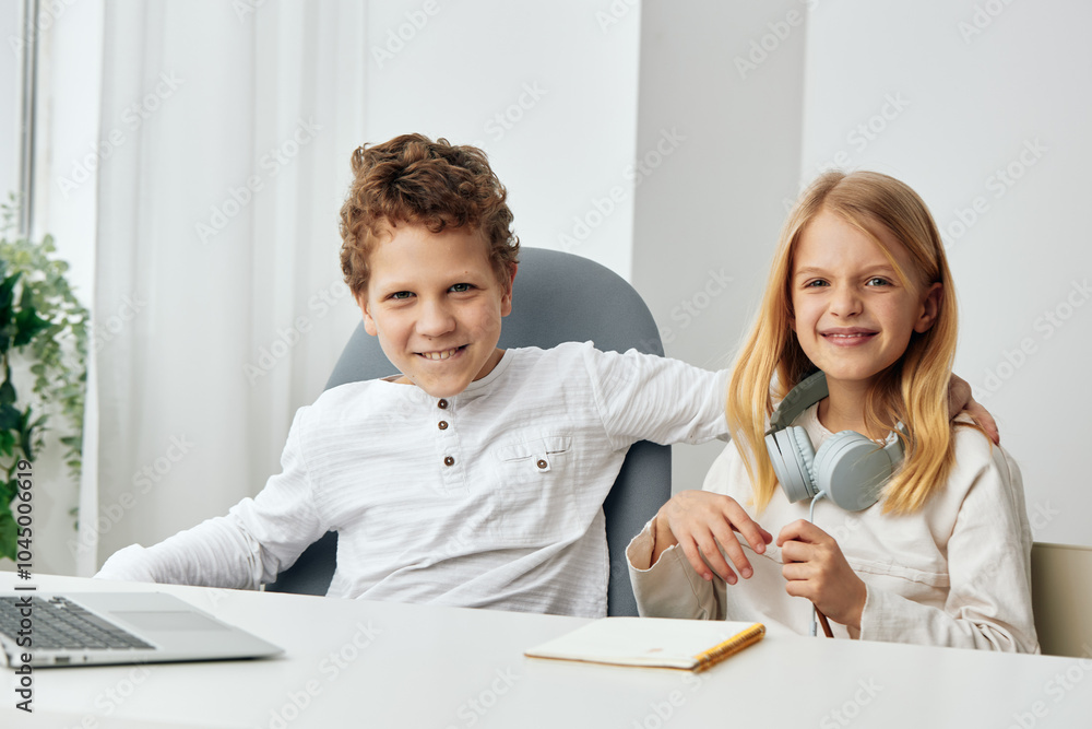 Happy Caucasian children studying at home with their laptops and headphones, immersed in elearning The two siblings, a boy and a girl, are sitting at a table in their living room, fully engaged in Happy Caucasian children studying at home with their laptops and headphones, immersed in elearning The two siblings, a boy and a girl, are sitting at a table in their living room, fully engaged in