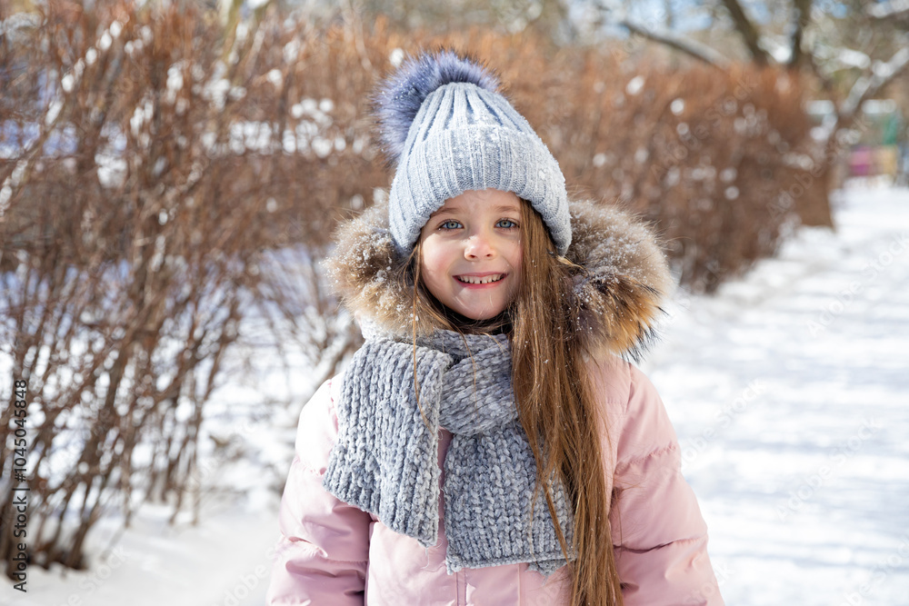 Happy little girl in warm pink coat and grey knitted hat has fun and walking in snowy winter park. Children outdoor activities concept. Happy family holidays time. High quality photo Happy little girl in warm pink coat and grey knitted hat has fun and walking in snowy winter park. Children outdoor activities concept. Happy family holidays time. High quality photo