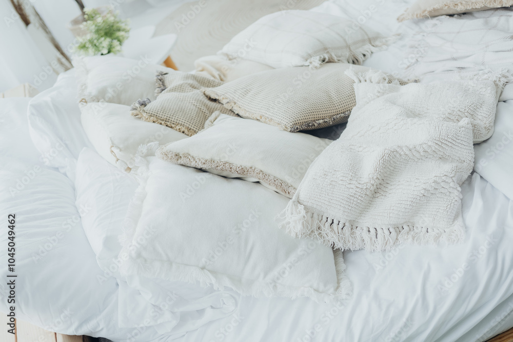 Fototapeta premium Cozy bed with textured pillows and blankets in a bright, airy room