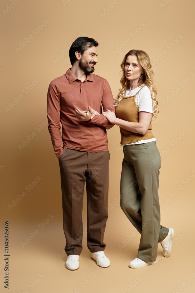 A middle aged couple smiles and chats closely while dressed casually. A middle aged couple smiles and chats closely while dressed casually.
