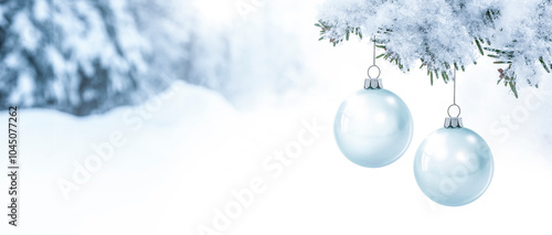 Gläserne Weihnachtskugeln an einem Tannenzweig vor einem verschneiten unschar...