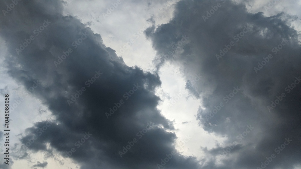 A dramatic sky with dark, ominous clouds. The clouds are thick and appear to be moving quickly. There are faint streaks of light visible through the clouds. A dramatic sky with dark, ominous clouds. The clouds are thick and appear to be moving quickly. There are faint streaks of light visible through the clouds.