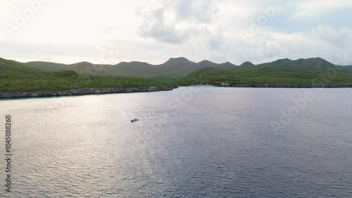 Aerial drone establishing overview of peaceful tropical bay at Kenepa Grande , capturing lush green hills surrounding the calm turquoise waters of the Caribbean photo