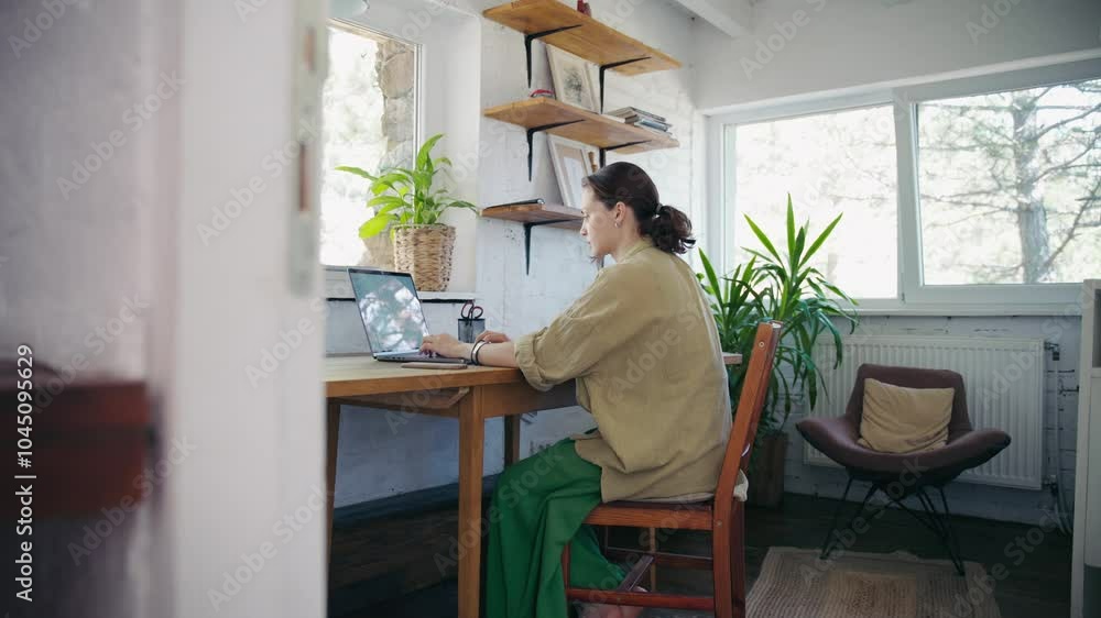 A young Caucasian woman is working on a laptop in her countryside cottage A young Caucasian woman is working on a laptop in her countryside cottage