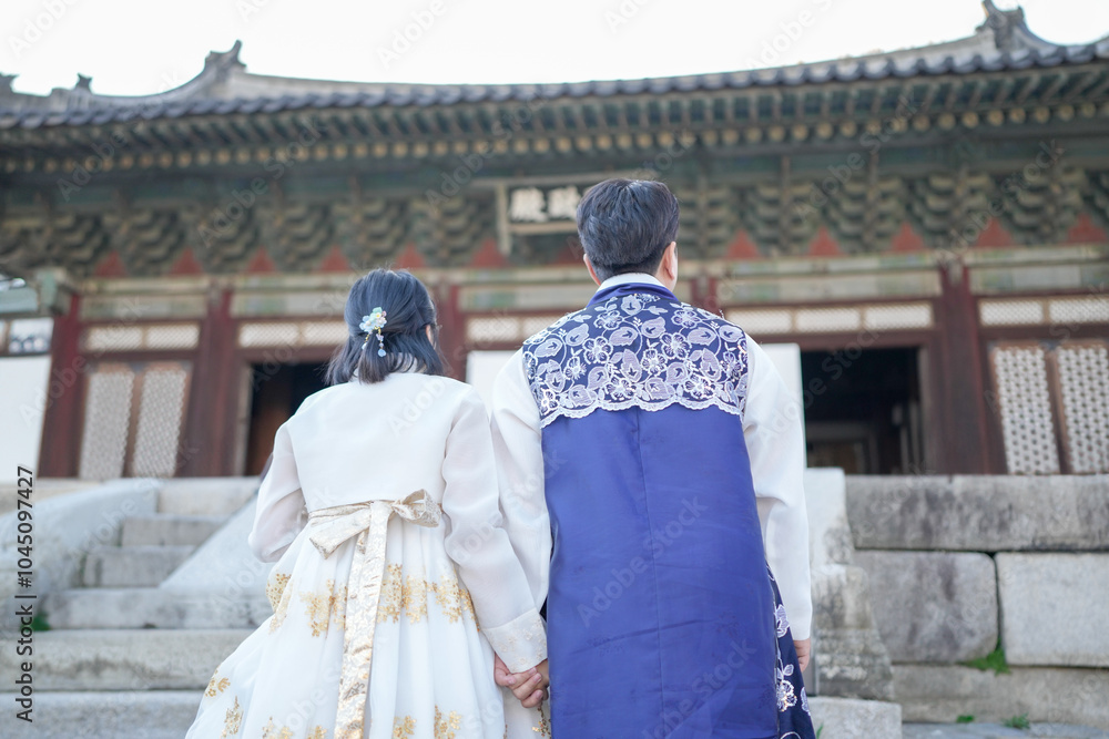 Fototapeta premium A Korean couple, a man in his 30s and a woman in her 20s, walks harmoniously through a historical building in Seoul, South Korea, wearing Hanbok.