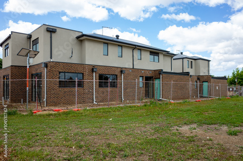Canvas Print A row of newly constructed two-story residential townhouses, surrounded by a temporary construction fence