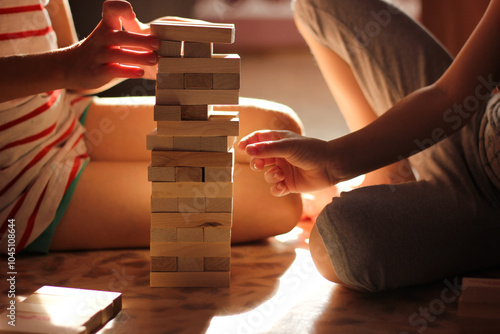 Children's hands in the sun room playing janga. Children's board games to develop memory and mind. Children's hands in the sunlight. Entertainment activity. Physical and mental skill game.