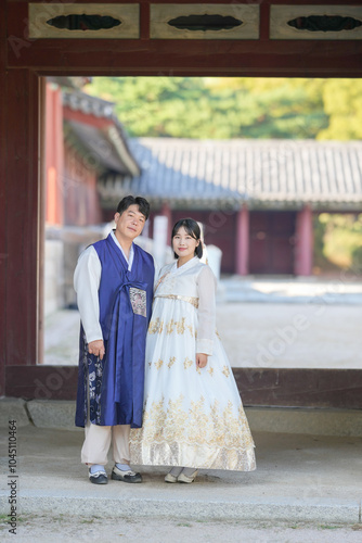 A Korean couple in their 30s and a woman in their 20s stand together in front of a historical building in Seoul, South Korea, wearing Hanbok.