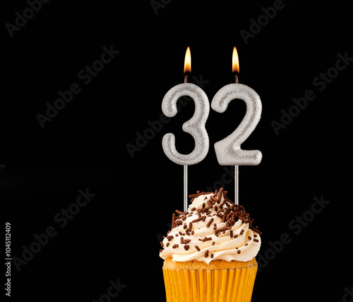 Birthday cupcake on black background - Number 32 shaped candles.