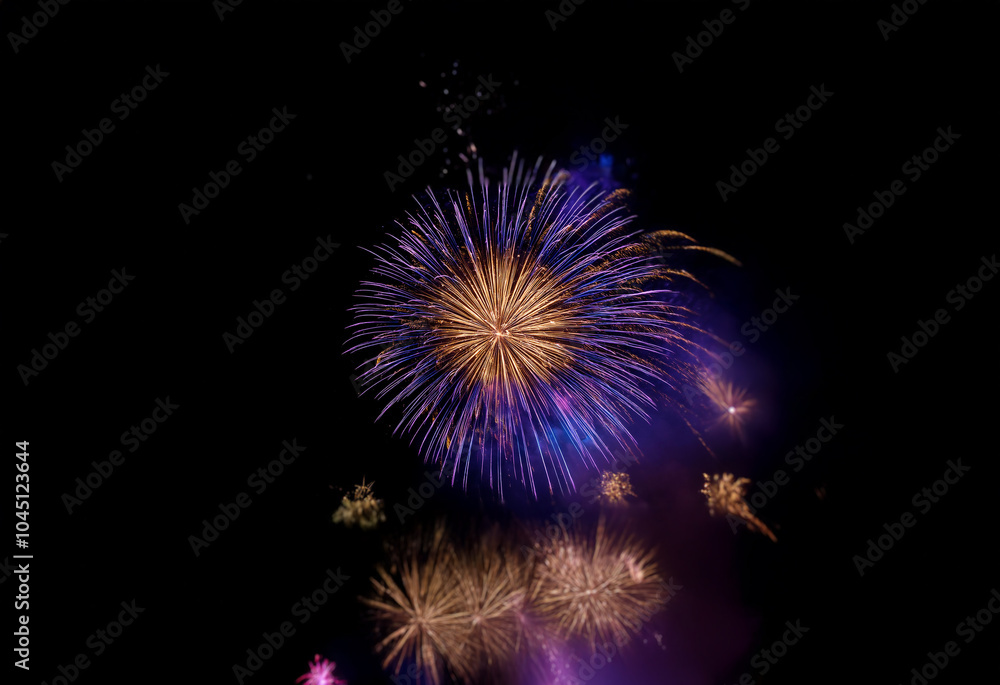 A single, isolated firework explodes in a vibrant display of purple and gold against a dark, black background. A single, isolated firework explodes in a vibrant display of purple and gold against a dark, black background.