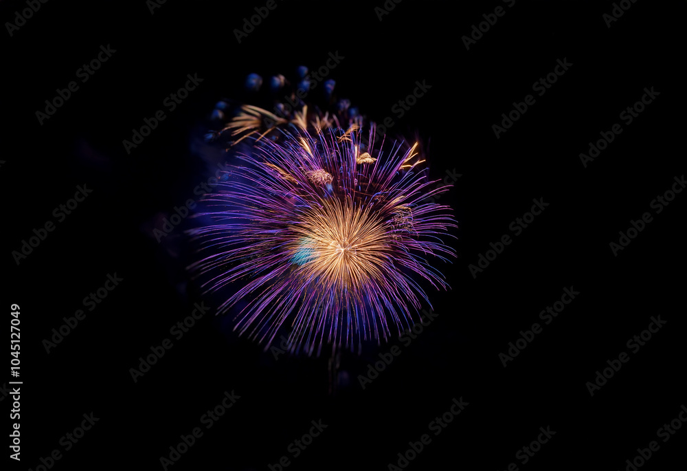 An isolated purple and yellow firework bursts against a black background. An isolated purple and yellow firework bursts against a black background.
