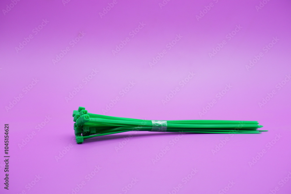 Fototapeta premium bundle of green zip ties isolated on purple background. Cable ties or cable ties, straps that can be used for various purposes.