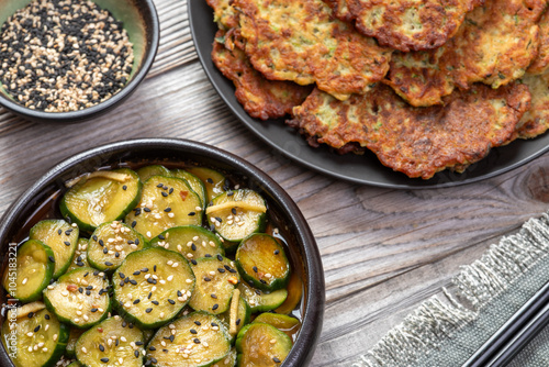 Zucchini and chickpea flour pancakes, sliced cucumbers pickled in soy sauce, and black and white sesame seeds. Vegan snack or lunch. photo