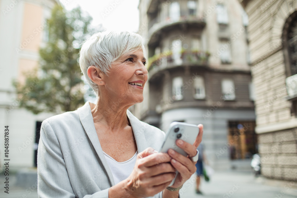 Smiling senior businesswoman using smartphone downtown Smiling senior businesswoman using smartphone downtown