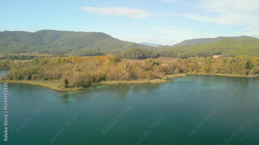 landscape featuring a body of water surrounded by lush greenery calm water reflects the clear blue sky above Trees lining the shore display green and autumnal colors, indicating a seasonal transition landscape featuring a body of water surrounded by lush greenery calm water reflects the clear blue sky above Trees lining the shore display green and autumnal colors, indicating a seasonal transition