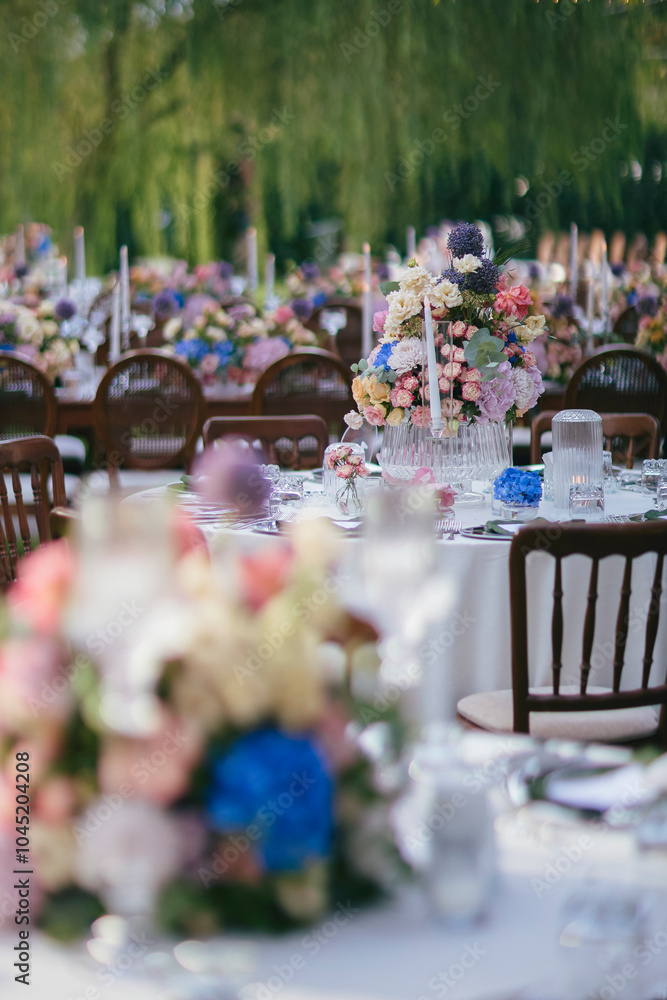 Outdoor Wedding Reception with Floral Centerpieces and Elegant Table Setting - A Romantic Garden Event